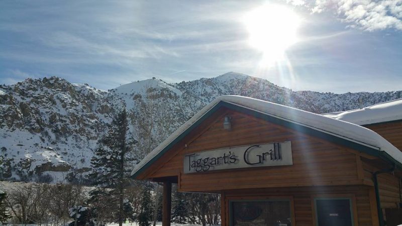 Taggart's grill during the winter with the sun shining bright above it and snonw covered mountains behind it